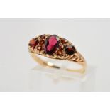 A 9CT GOLD GARNET RING, designed as a central oval garnet flanked by three circular garnets and a