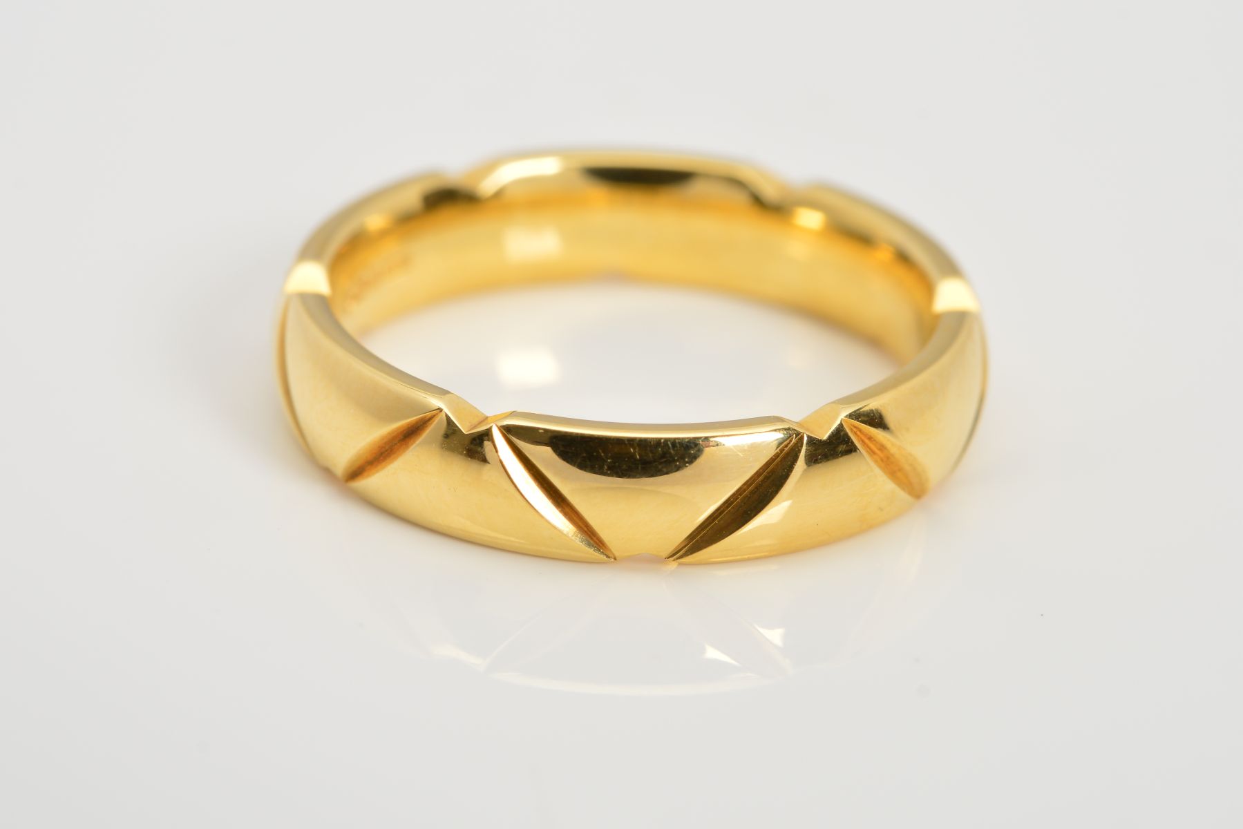 A MODERN 18CT GOLD WEDDING RING, with chevron carved detail, measuring approximately 4.0mm in width,