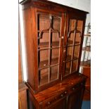 A GEORGIAN MAHOGANY ASTRAGAL GLAZED TWO DOOR BOOKCASE above two drawers above double panelled