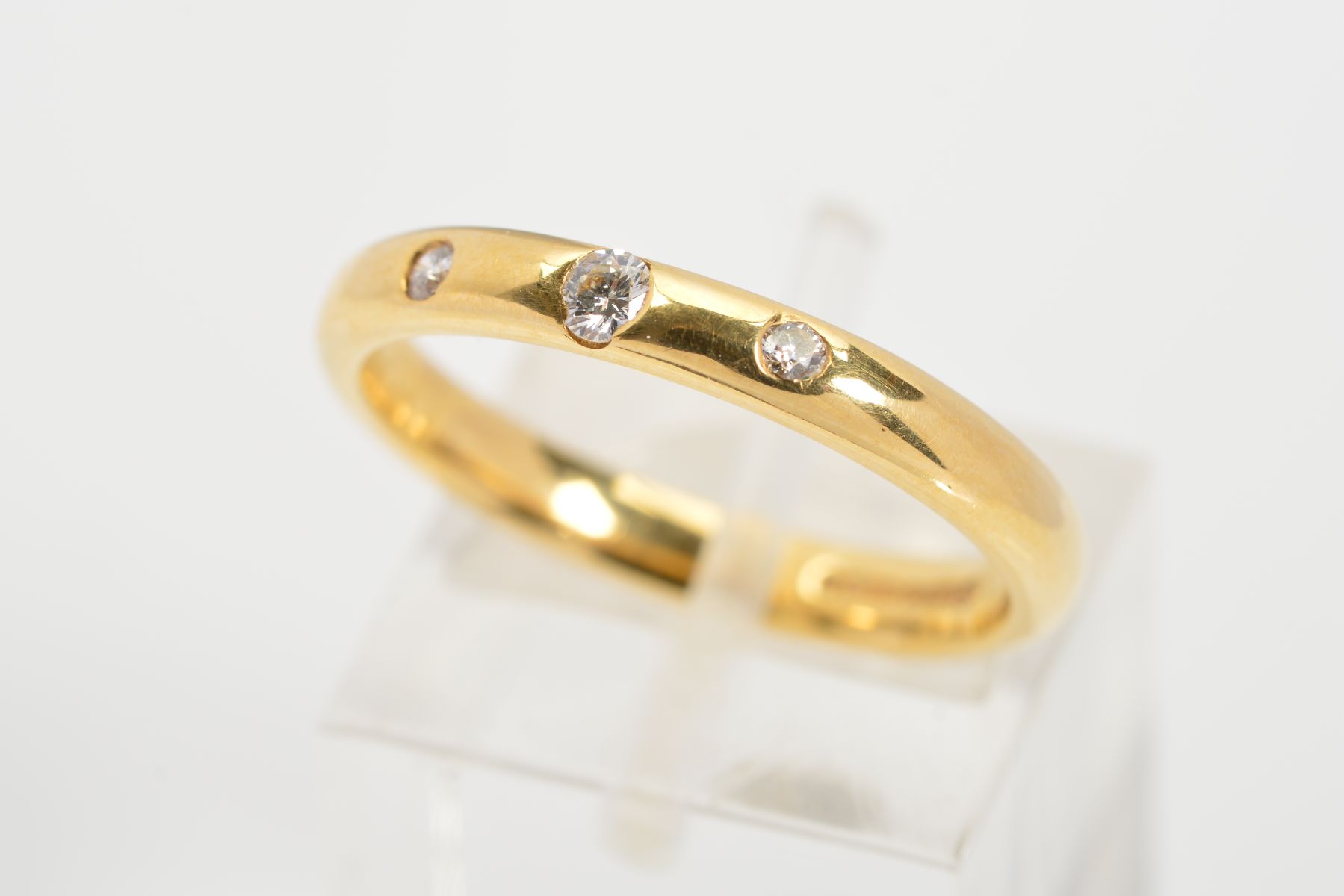 AN 18CT GOLD DIAMOND SET BAND RING, the plain D shape band flush set with three graduated