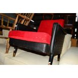 A 1950'S BLACK VINYL AND RED UPHOLSTERED FIRESIDE CHAIR on four cylindrical tapering legs