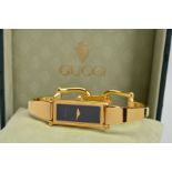 A LADY'S GUCCI WRISTWATCH, gold plated rectangular case, black dial, gold tapering hands, quartz