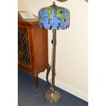 A TIFFANY STYLE STANDARD LAMP with a blue and green ground, shade on column upright and shaped base,