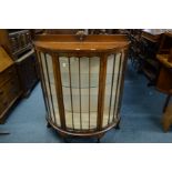 AN EARLY 20TH CENTURY OAK DEMI LUNE GLAZED SINGLE DOOR DISPLAY CABINET on ball and claw feet,