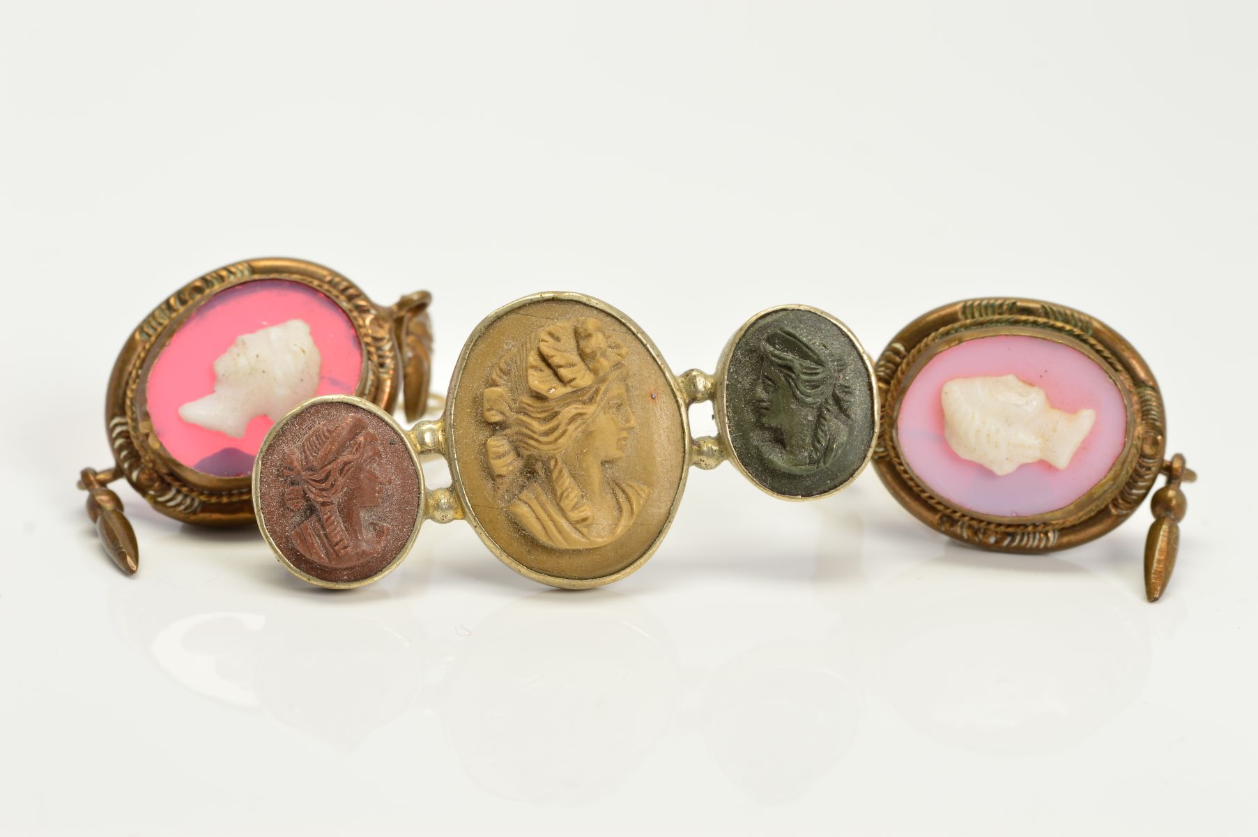 A VICTORIAN LAVA CAMEO BROOCH depicting three maidens in profile, pin and hook catch, together