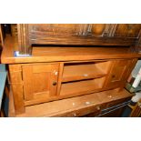 A REPRODUCTION GOLDEN OAK TV STAND with two cupboard doors, width 120cm x depth 44cm x height 50cm