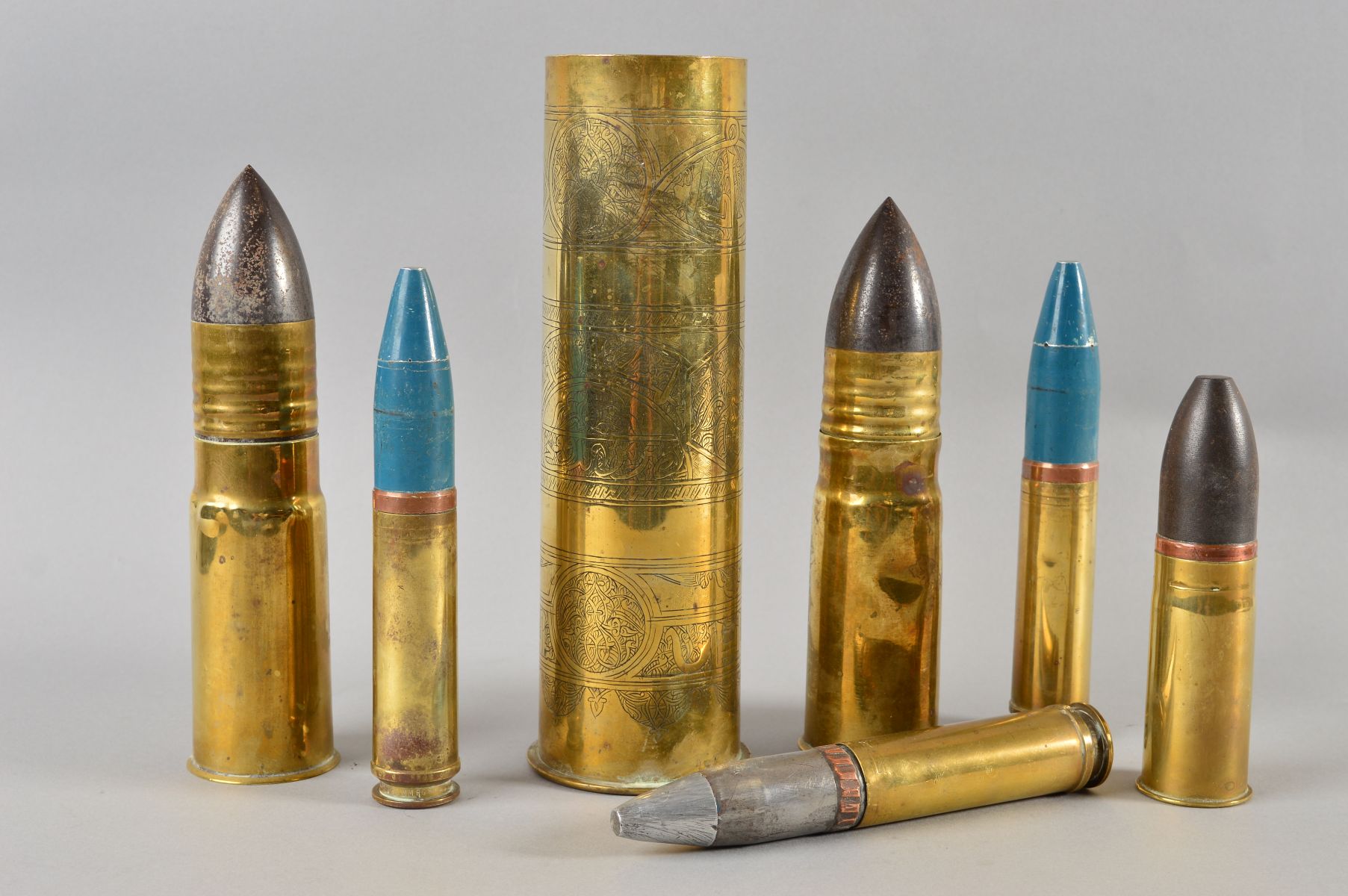 A BOX CONTAINING SIX MILITARY SHELLS OF VARIOUS CALIBRES INERT, and a larger shell which has been