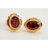 A PAIR OF GARNET STUD EARRINGS, each designed as a central oval garnet in a collet setting within