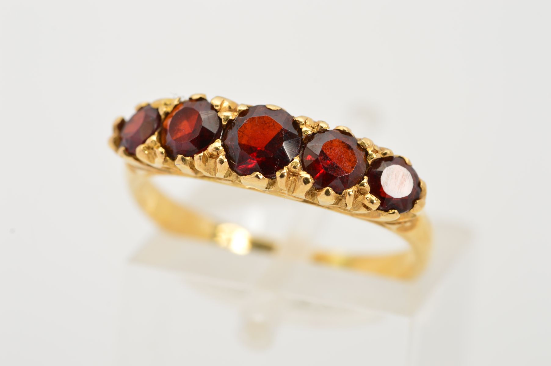 AN 18CT GOLD FIVE STONE GARNET RING, designed as a graduated row of five circular garnets to the