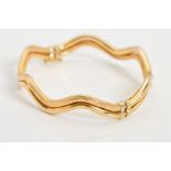 A 9CT GOLD HINGED BANGLE, designed as two parallel wavy tubes, one textured one polished, to the