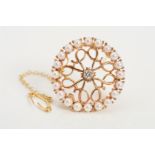 A 14CT DIAMOND AND SEED PEARL BROOCH, of circular openwork scrolling design, centrally set with a