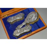 A LATE VICTORIAN SILVER DRESSING TABLE BRUSH SET, boxed, all embossed with outdoor scenes of
