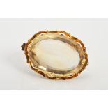 A LATE VICTORIAN GOLD CITRINE BROOCH, of oval outline with repeated curved pattern surround,
