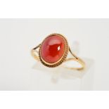 A 9CT GOLD GEM RING, designed as a central oval red gem cabochon within a collet setting and rope