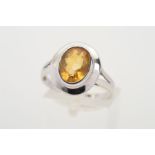 A 9CT WHITE GOLD CITRINE RING, the oval citrine within a collet setting to the plain surround to the