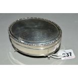 A GEORGE V OVAL SILVER TRINKET BOX, engine turned hinged cover, red velvet lined interior, on four