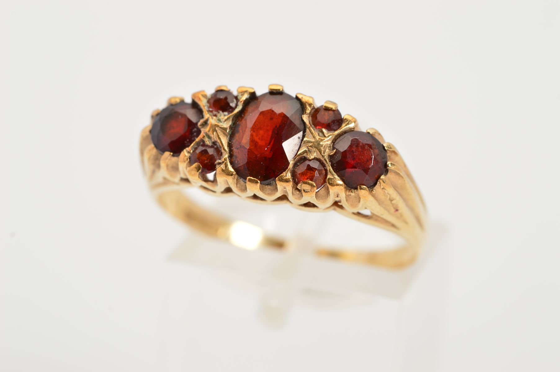 A 9CT GOLD GARNET RING, designed as a central oval garnet flanked by a circular garnet interspaced