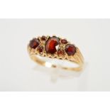 A 9CT GOLD GARNET RING, designed as a central oval garnet flanked by a circular garnet interspaced