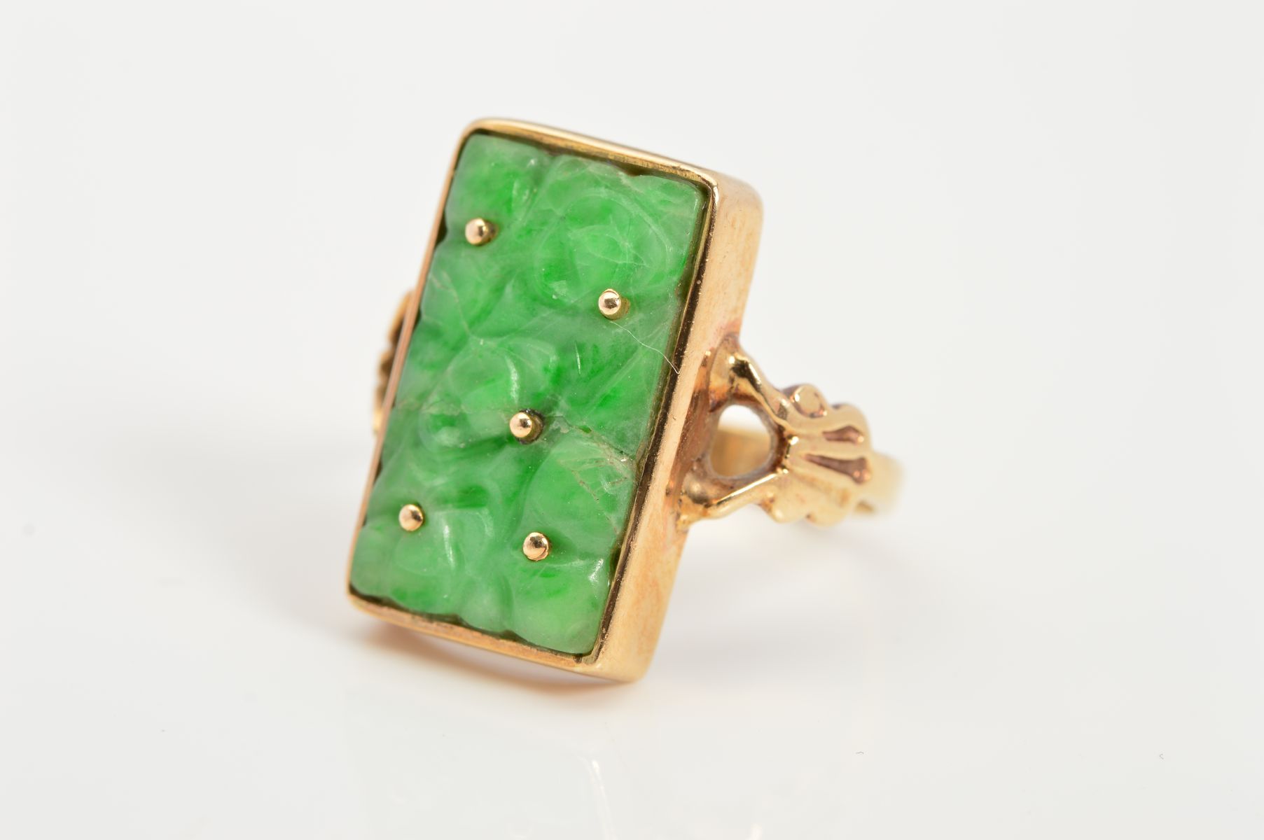 A 9CT GOLD JADE RING, designed as a rectangular carved jade panel within a collet setting to the