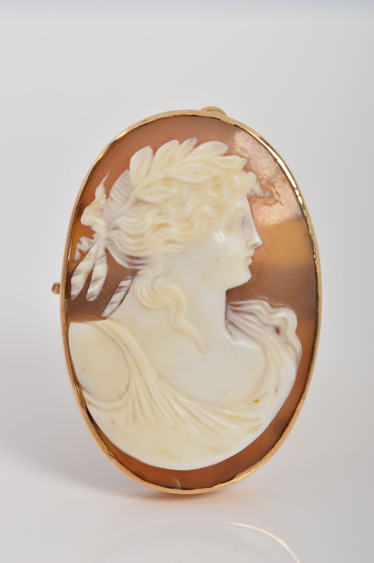 A CAMEO BROOCH, of oval outline, carved to depict a bacchante in profile, to the plain collet