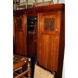 AN EDWARDIAN WALNUT THREE DOOR COMPACTUM WARDROBE, the central mirrored door revealing four linen