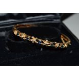 A 9CT GOLD DIAMOND AND SAPPHIRE BANGLE, the hinged bangle with open detail, the front half bangle