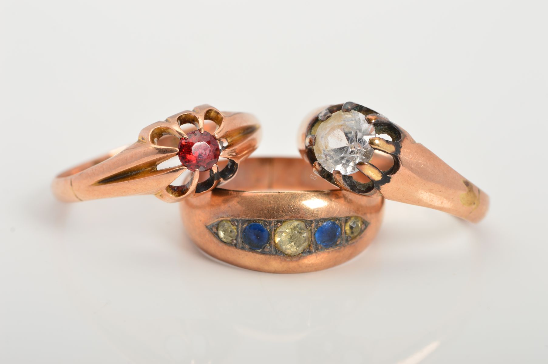 THREE EARLY 20TH CENTURY 9CT GOLD GEM SET RINGS, the first claw set with a circular garnet, the