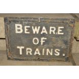 A CAST IRON SIGN BEWARE OF TRAINS, raised white lettering on a black background, length