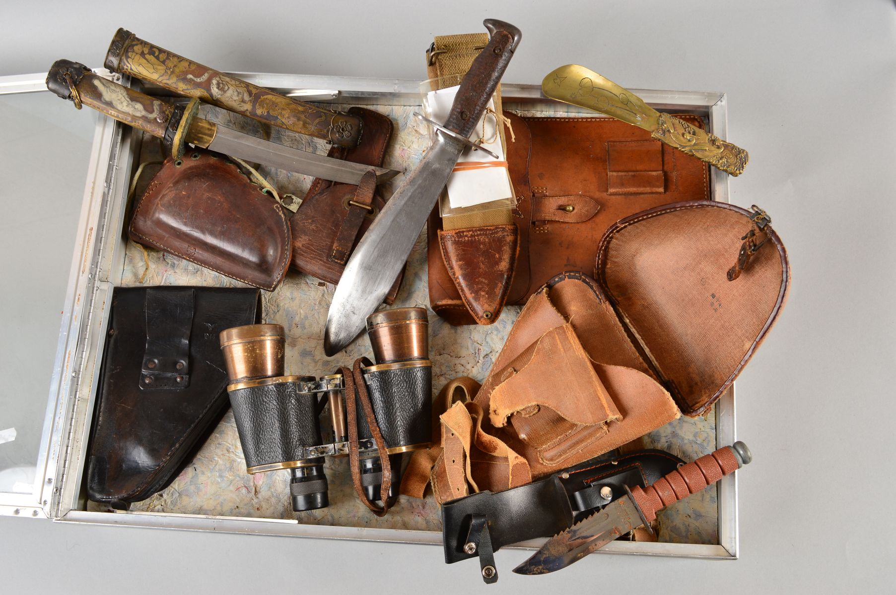 A LARGE GLASS TOP DEALER STYLE DISPLAY CASE CONTAINING THE FOLLOWING ITEMS, brown leather WWII era