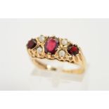 A 9CT GOLD GARNET AND SEED PEARL RING, designed as a central oval garnet flanked by a circular