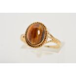 A 9CT GOLD TIGER'S EYE RING, designed as an oval tiger's eye cabochon within a collet setting and