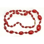 A RED PLASTIC BEAD NECKLACE designed as forty three graduated barrel shape beads measuring