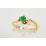 AN EMERALD RING, designed as a circular emerald within a four claw setting to the cross over