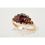 A 9CT GOLD GARNET DRESS RING, designed as a central oval garnet set to each shoulder with six