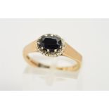 A 9CT GOLD SAPPHIRE AND DIAMOND CLUSTER RING, designed as a central claw set oval sapphire within