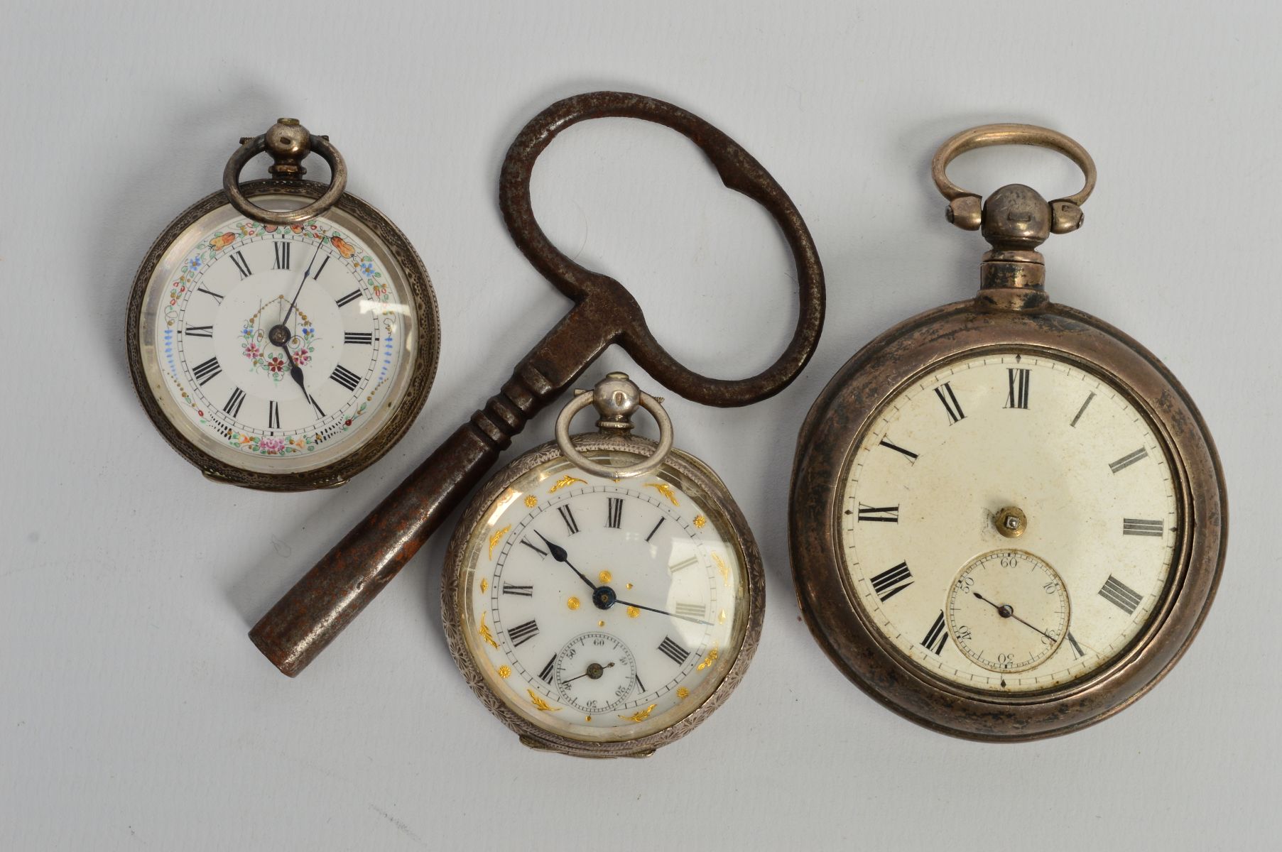 THREE EARLY 20TH CENTURY SILVER OPEN FACE POCKET WATCHES AND A CLOCK KEY, all with Roman numeral