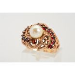 A CULTURED PEARL AND GARNET DRESS RING, designed as a central spherical pearl to the scrolling