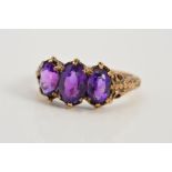 A 9CT GOLD AMETHYST THREE STONE RING, designed as three graduated oval amethysts within claw