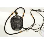 A CONTINENTAL BLACK GLASS PENDANT, designed as the head of a God suspended from a braided cord