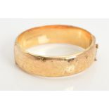 A 9CT GOLD HINGED BANGLE, the front half bangle with engraved scrolling decoration, with safety