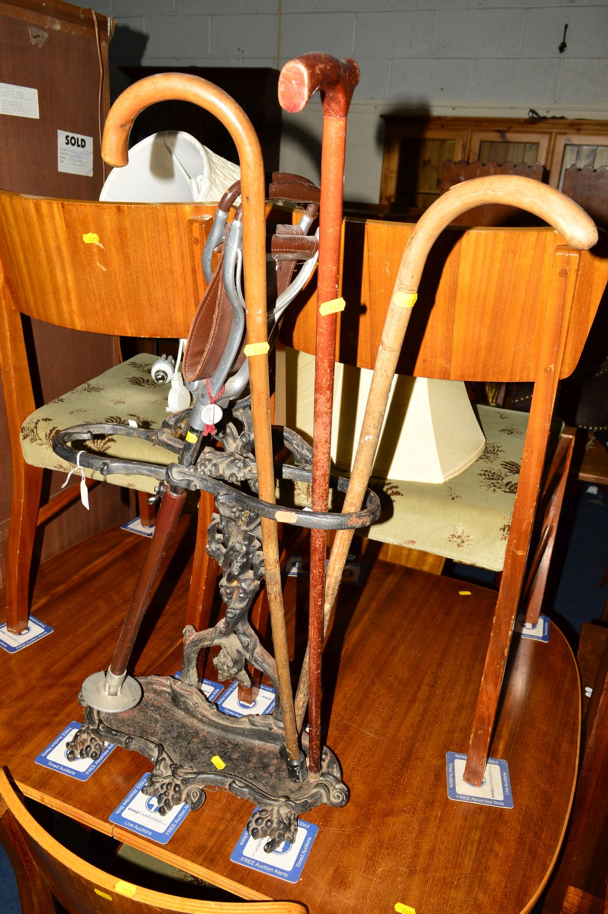 A VICTORIAN CAST IRON UMBRELLA STAND containing three walking sticks and a shooting stick (5)