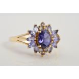 A 9CT GOLD TANZANITE CLUSTER RING, designed as a central oval tanzanite within a four claw setting
