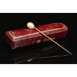 A VICTORIAN NATURAL PEARL STICK PIN, measuring approximately 63mm in length, accompanied with a