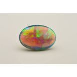 AN OVAL CABOCHON BLACK OPAL, showing flashes of electric blues, greens, orange and yellow colours,