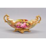 A ROYAL WORCESTER TWIN HANDLED BOAT SHAPED PEDESTAL BOWL, painted with pink roses, signed by Jack