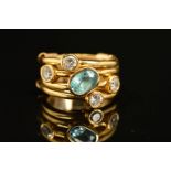 A MODERN DIAMOND AND BLUE ZIRCON DRESS RING, comprised four gold bands rub over set with one oval