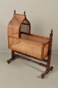 A VICTORIAN MAHOGANY AND STAINED BEECH AND CANED CRADLE, lancet arch shaped canopy with two turned