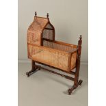 A VICTORIAN MAHOGANY AND STAINED BEECH AND CANED CRADLE, lancet arch shaped canopy with two turned