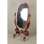 A VICTORIAN MAHOGANY OVAL CHEVAL MIRROR, on ornate carved supports in the form of birds, possibly