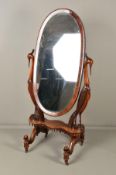 A VICTORIAN MAHOGANY OVAL CHEVAL MIRROR, on ornate carved supports in the form of birds, possibly